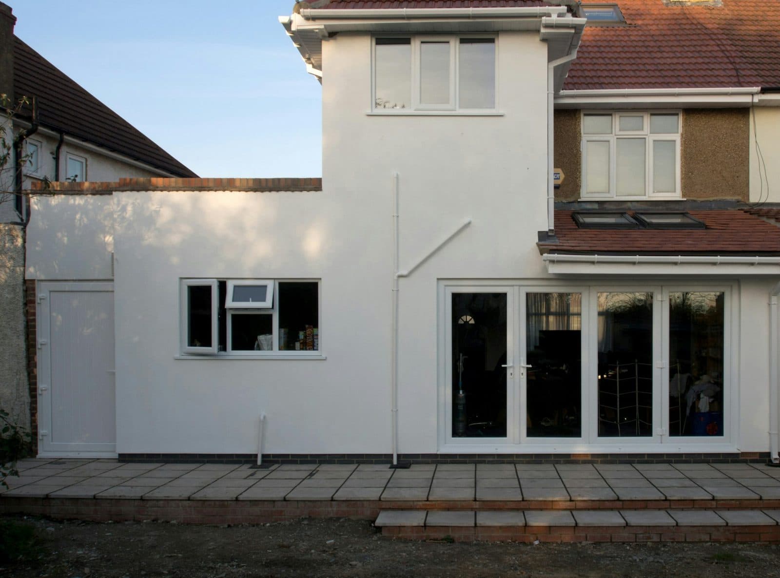 The same house after a rendered rear addition with French doors and a new patio