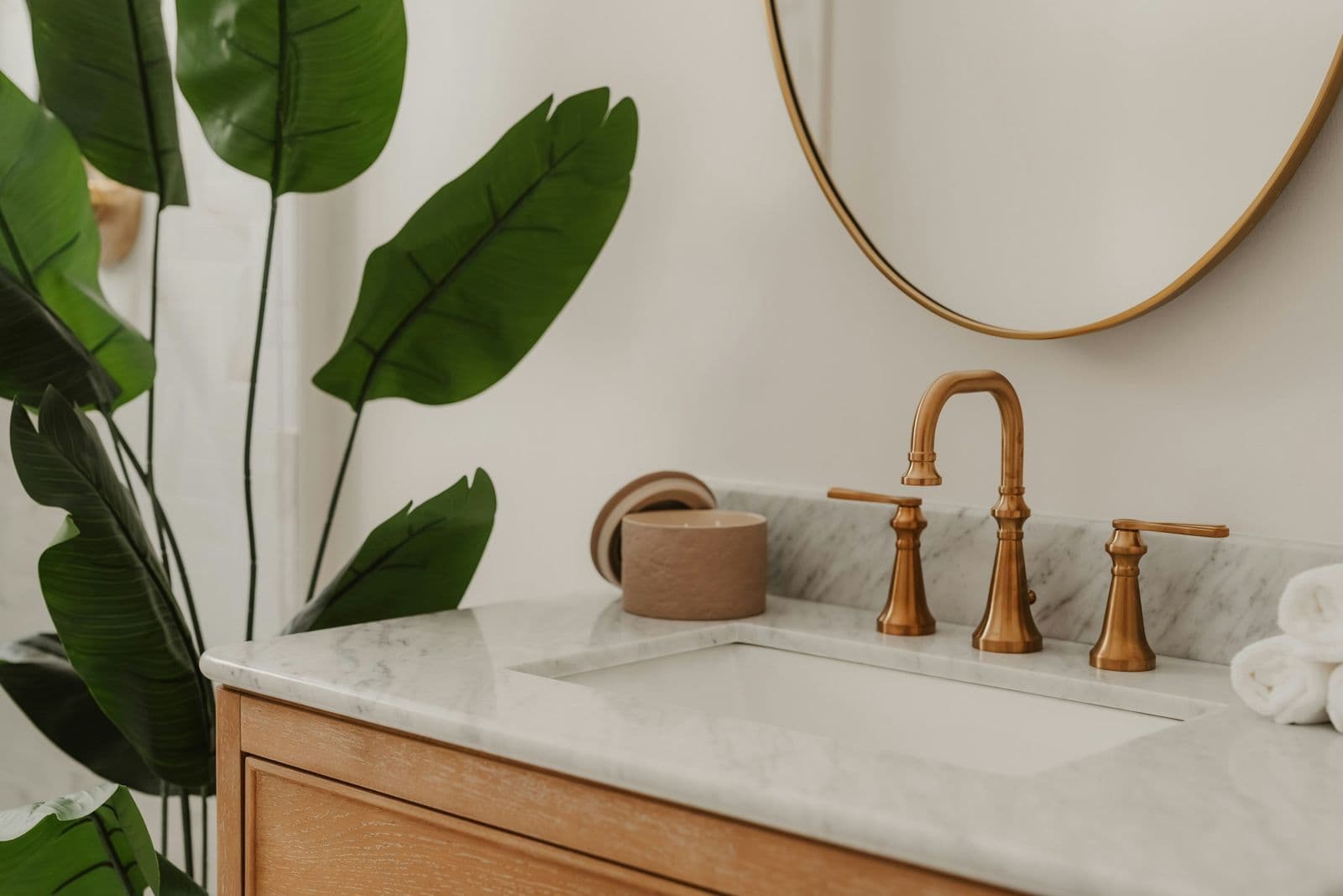 Brass faucet on a marble vanity top with a wooden cabinet