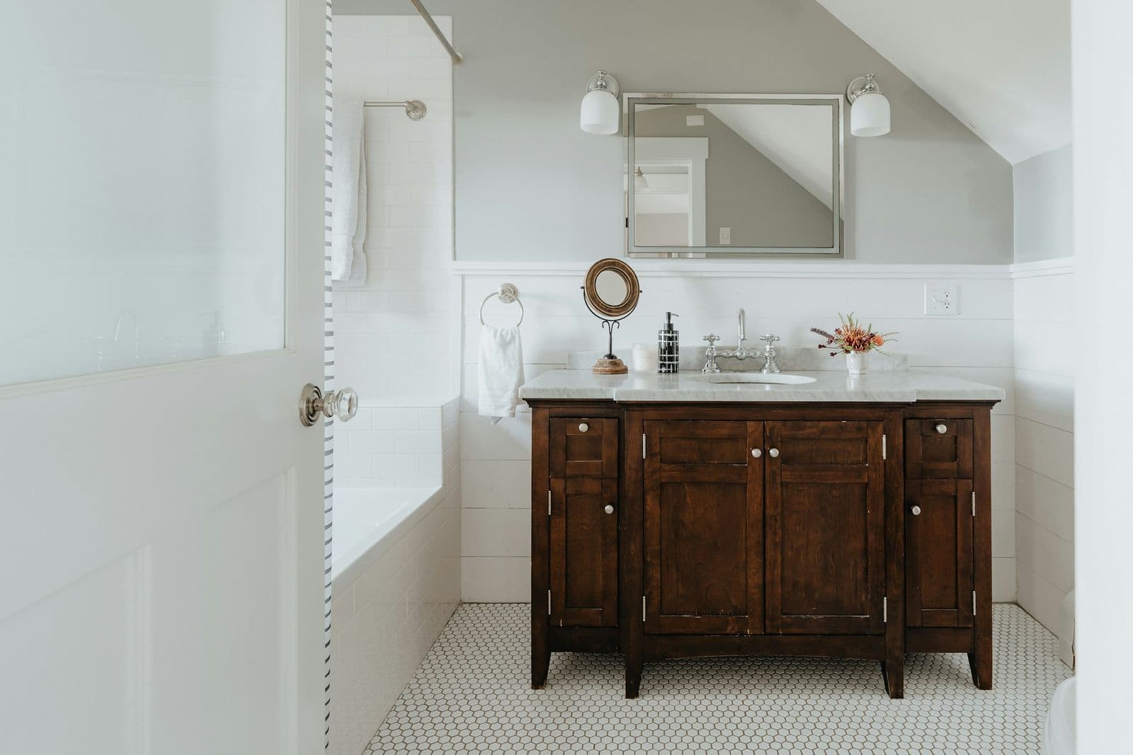 Wood furniture vanity in a white tiled bathroom