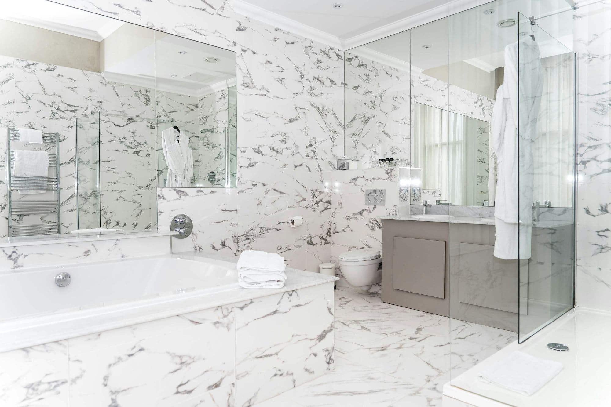 Marble primary bathroom with soaking tub and frameless glass shower