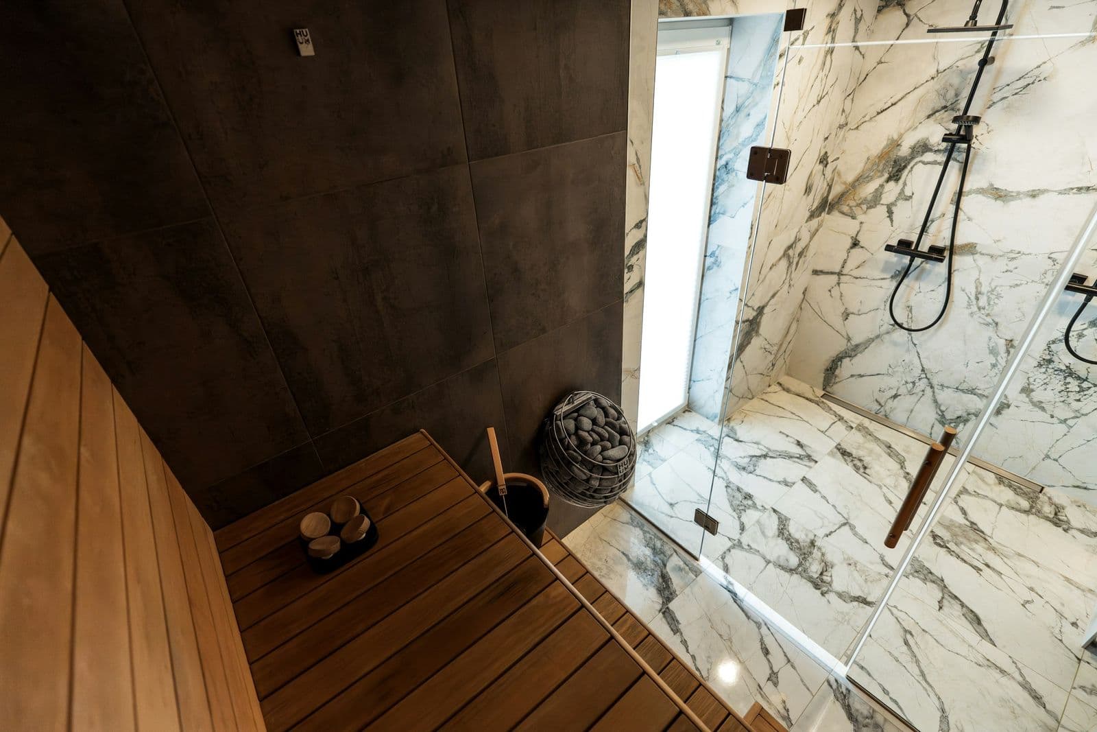 Book-matched porcelain walk-in shower beside a cedar sauna bench