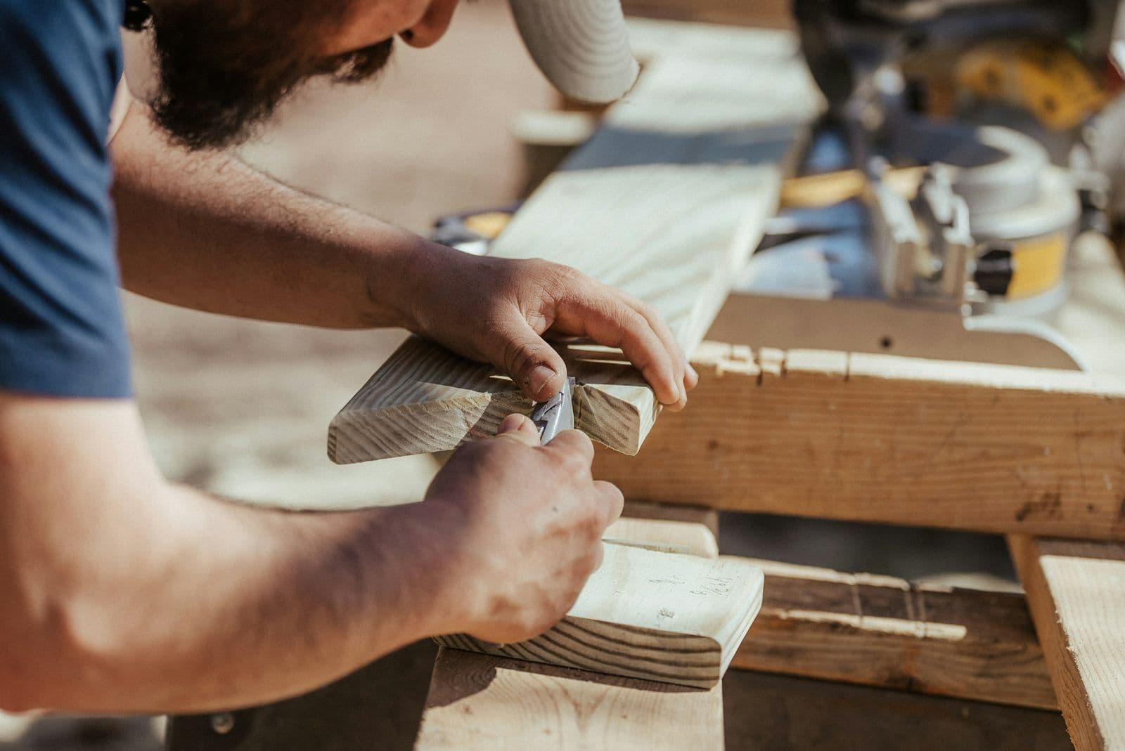 Carpenter in a cap shaping a board on a job site
