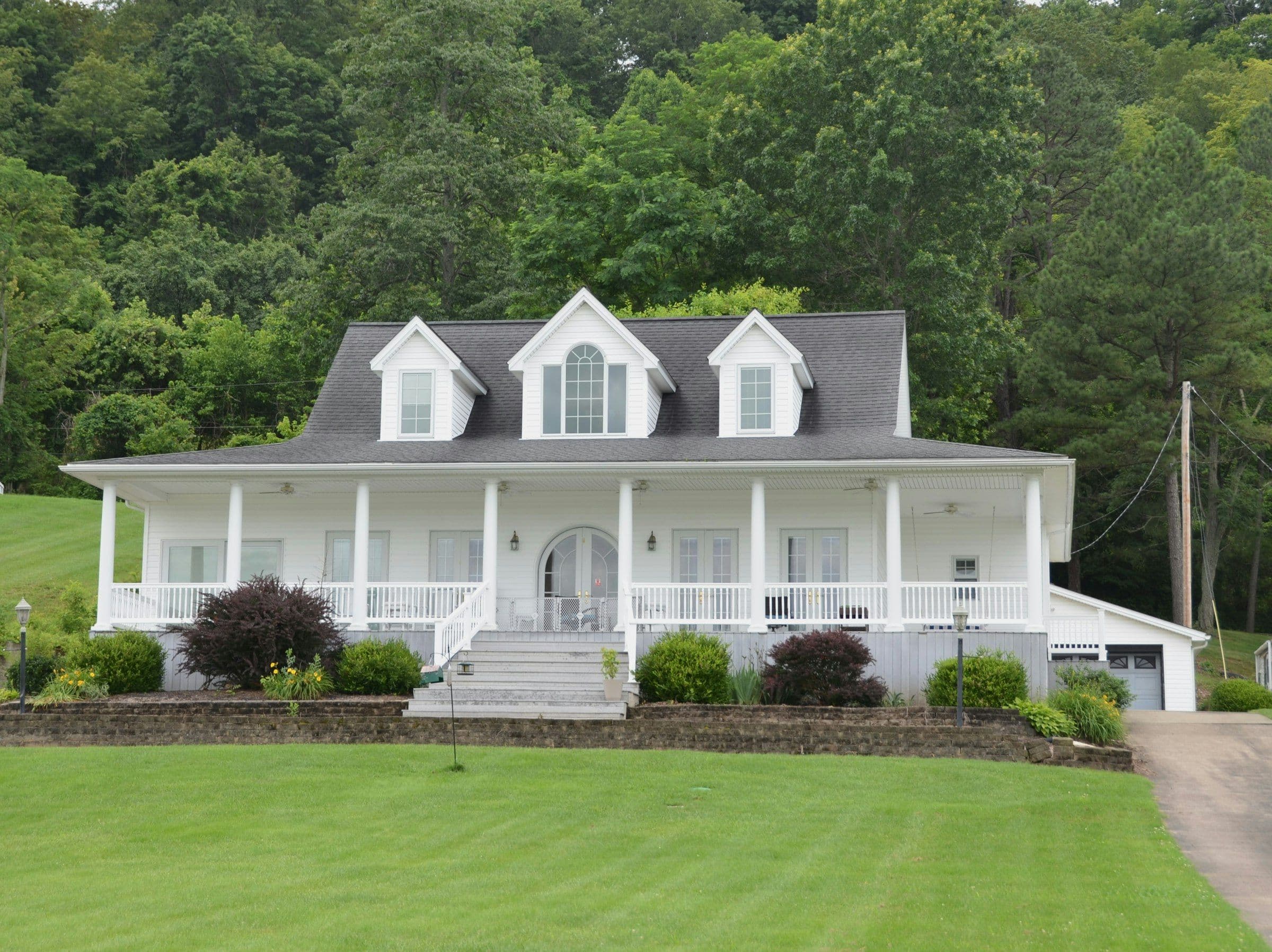 White two-story home with a wide covered front porch and a manicured lawn