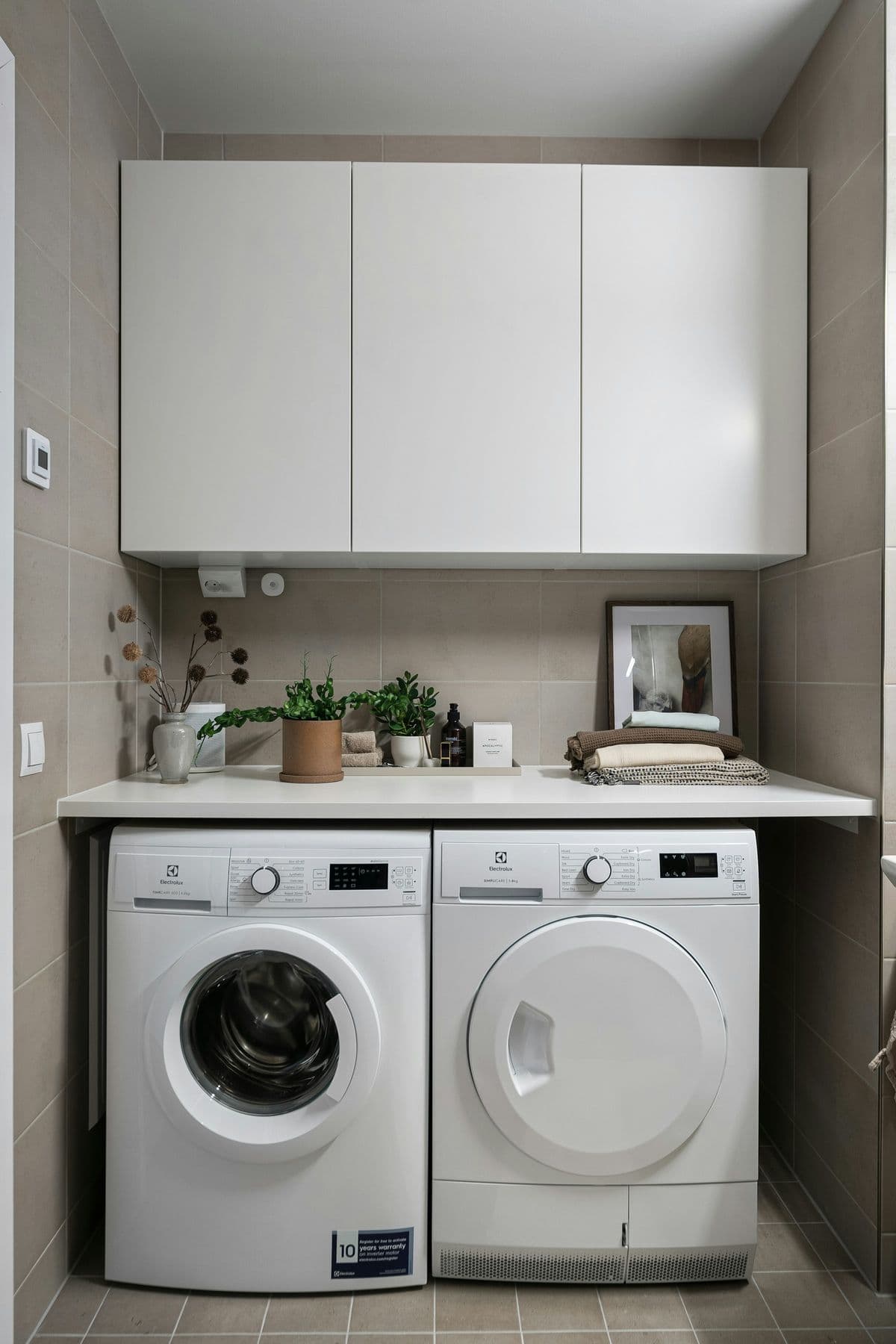 Compact laundry with side-by-side machines and upper cabinets