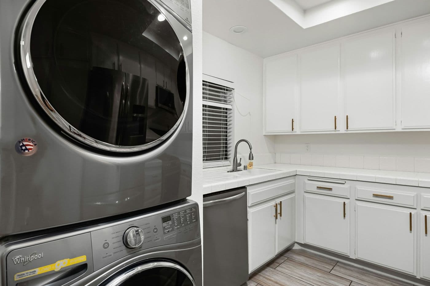 Laundry room with stacked washer and dryer and white cabinets