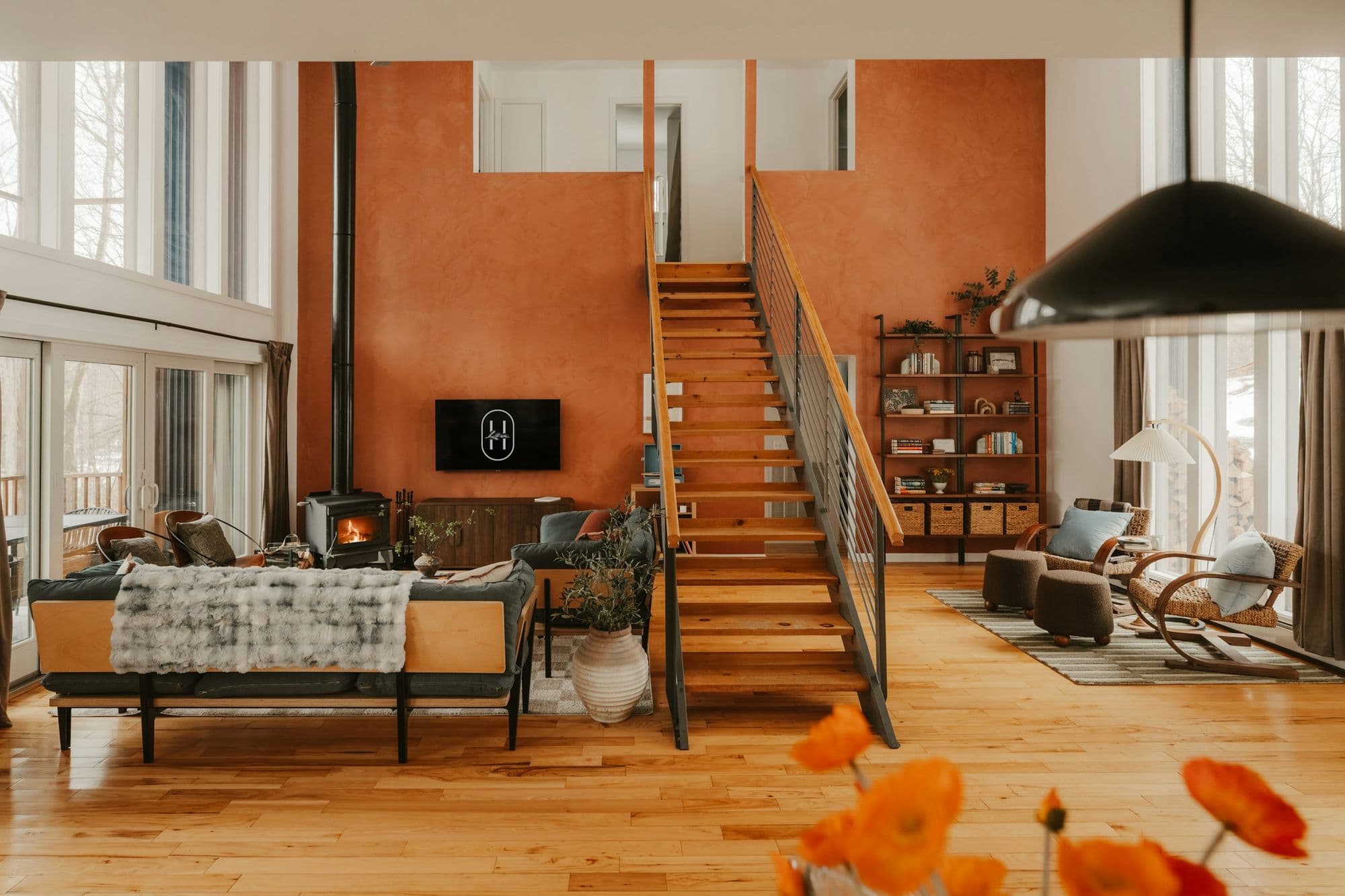 Open living room with a timber staircase and wood stove