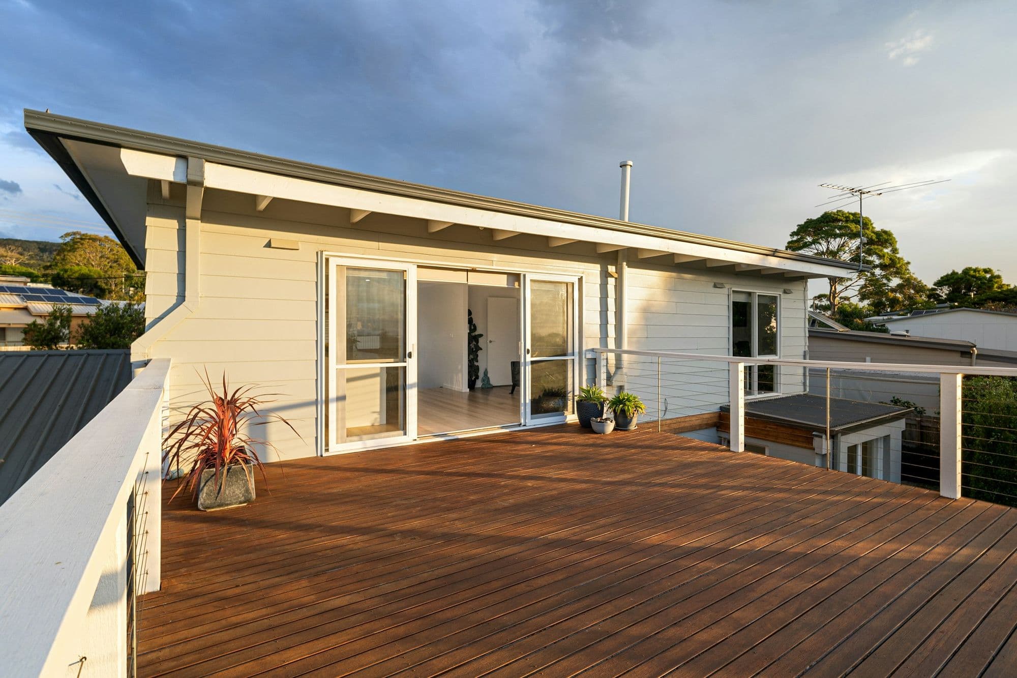 New wood deck off the back of a white house